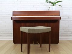 a piano with a stool in front of it and a potted plant on top