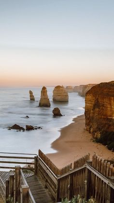 stairs lead down to the beach and into the water at sunset with cliffs in the background