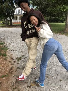 two people standing next to each other on a gravel road