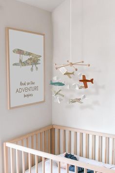 a baby's crib with an airplane mobile hanging from the ceiling above it