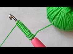 a green ball of yarn and a pink crochet hook