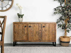 a potted plant sitting on top of a wooden cabinet next to a wall clock