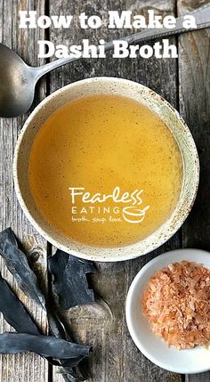 a bowl filled with broth next to spoons on top of a wooden table