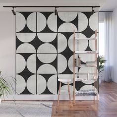 a black and white geometric wall mural in a living room with wooden flooring, bookshelf and plant