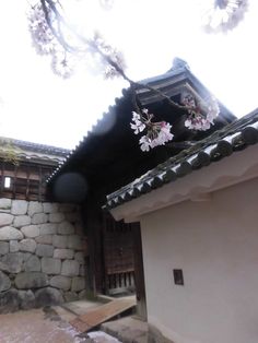 a building with flowers on the roof and in front of it is a stone wall