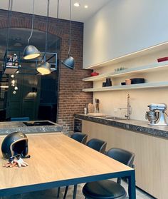 a kitchen with a table and chairs in front of a brick wall that has lights hanging from it