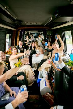 a group of people sitting in the back of a bus with drinks and food on it