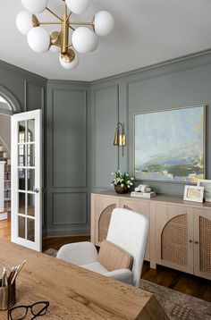 a living room with green walls and white chairs in front of a large painting on the wall