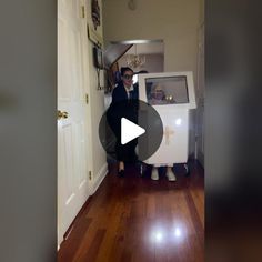 a man standing next to a washing machine in a room with wooden floors and white walls