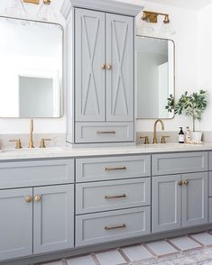 a bathroom with two sinks, mirrors and cabinets in grey colors on the countertop