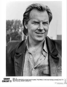 a black and white photo of a man in a leather jacket smiling at the camera