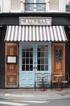 a restaurant with blue doors and striped awnings