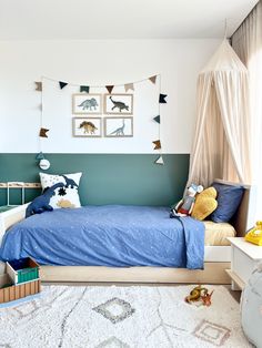 a child's bedroom decorated in blue and white with dinosaur pictures on the wall