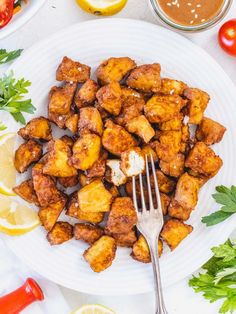 a white plate topped with tater tots next to sliced lemons and tomatoes