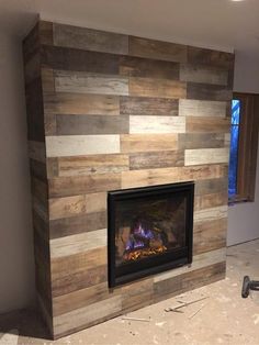 a living room with a fire place in the center and wood paneling on the walls