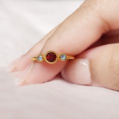 "GENERAL INFORMATION * Materials: 18K Vermeil Gold (2.5 Micron Gold plating on a 925 Sterling Silver Base) * Gemstone: Garnet & Labradorite * Style - Minimalist/Stacking Ring * Stone Size: 2 & 4mm Round * Weight: 1.14 gms * Finish: High Polish * Quantity: 1 piece CUSTOM RING SIZES * Not seeing your ring size listed? Select the \"Custom Ring Size\" option and put a note with your ring size at the checkout. * After we receive your order, we will reach out to confirm all sizing details. ABOUT THE PRODUCT This gorgeous ring is made of 18K Vermeil Gold, giving it a stunning shine that will turn heads. The three-stone setting showcases the centre gemstone surrounded by two smaller stones and delicately placed on a beautiful band. Three stone rings embody the romantic journey of two lovers, telli Dainty Gemstone Midi Rings As Gift, Dainty Gemstone Midi Rings For Gifts, Dainty Rings With Gemstone Accents, Dainty Birthstone Ring With Gemstone Accents, Birthstone Ring Gift For Her, Minimalist Women, Style Minimalist, Handmade Gold, Three Stone Rings