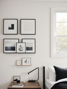 a bedroom with white walls and pictures on the wall