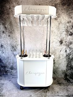 a white cart with wine glasses on top and the word champagne written in cursive writing