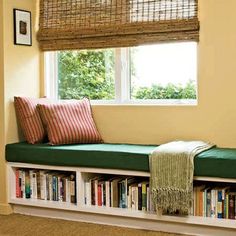 a window seat with books on it in front of a window