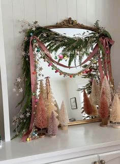 a mirror sitting on top of a dresser covered in christmas trees and garlands with lights