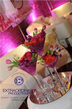 two martini glasses filled with flowers on top of a table