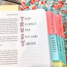 an open book sitting on top of a table next to colorful papers with writing on them