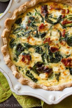 a quiche with spinach and cheese in a white dish on a green napkin