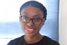 a woman wearing glasses is smiling for the camera while standing in front of a window