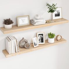 two wooden shelves with pictures, books and plants on them in front of a white wall