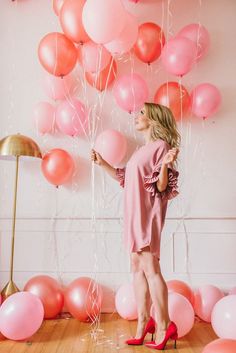 a woman standing in front of pink balloons