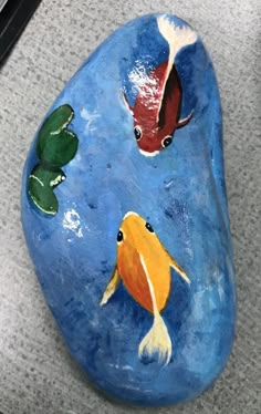 a painted rock with two goldfish on it