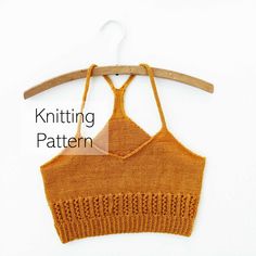 an orange knitted crop top hanging on a wooden hanger with the words knitting pattern below it