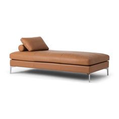 a tan leather chaise lounger with two pillows on it's backrest