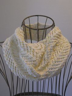 a white knitted scarf sitting on top of a metal stand