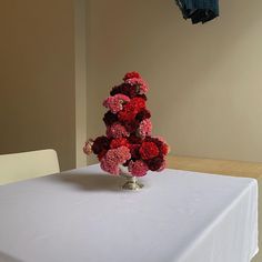 a white table topped with a vase filled with red and pink flowers