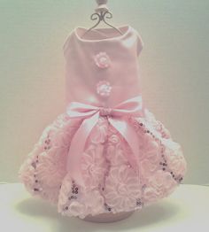 a pink dress with flowers on it and a bow at the waist, sitting on top of a white table