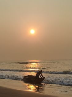 a person sitting on a small boat in the water at sunset or sunrise, with the sun behind them