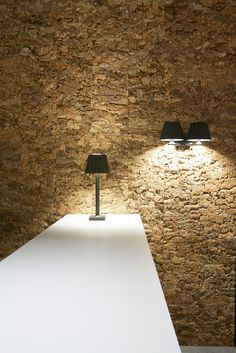 a table with two lamps on it in front of a wall that is made out of stone