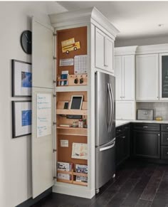 a kitchen with white cabinets and black flooring, an open refrigerator freezer is in the corner