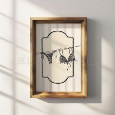 an empty wooden frame hanging on a wall with some clothes hung to dry in front of it