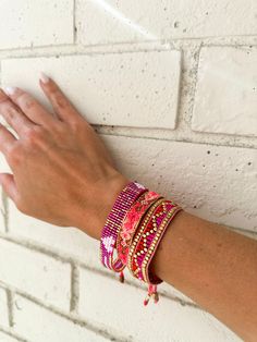 a woman's hand is holding onto a brick wall with bracelets on it