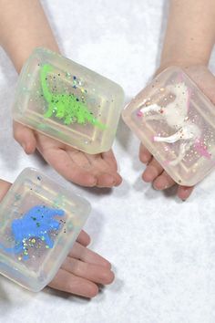 three children's hands holding plastic containers filled with glitter and confetti shapes