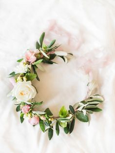 a flower crown on top of a white bed with pink and green flowers in the middle