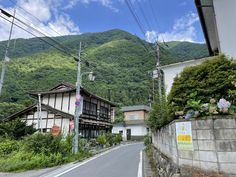 an empty street in front of a mountain side house with power lines above the road