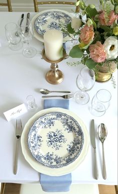 a table set with plates, silverware and flowers