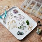 several pairs of scissors and other jewelry on a tray next to some beads, stones and seashells