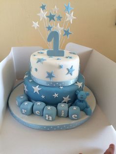 a blue and white birthday cake with stars on the top is sitting in a box