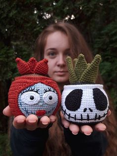 two crocheted pots with faces on them, one is wearing a red hat and the other has a green plant in it