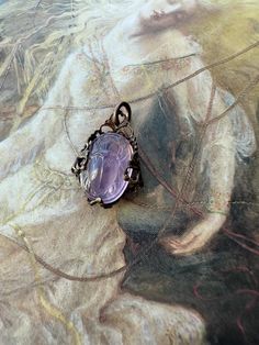 a necklace with a purple stone in the center on a painting background that looks like it has been painted