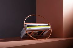 a magazine rack with magazines on it in front of a pink and gray wall,